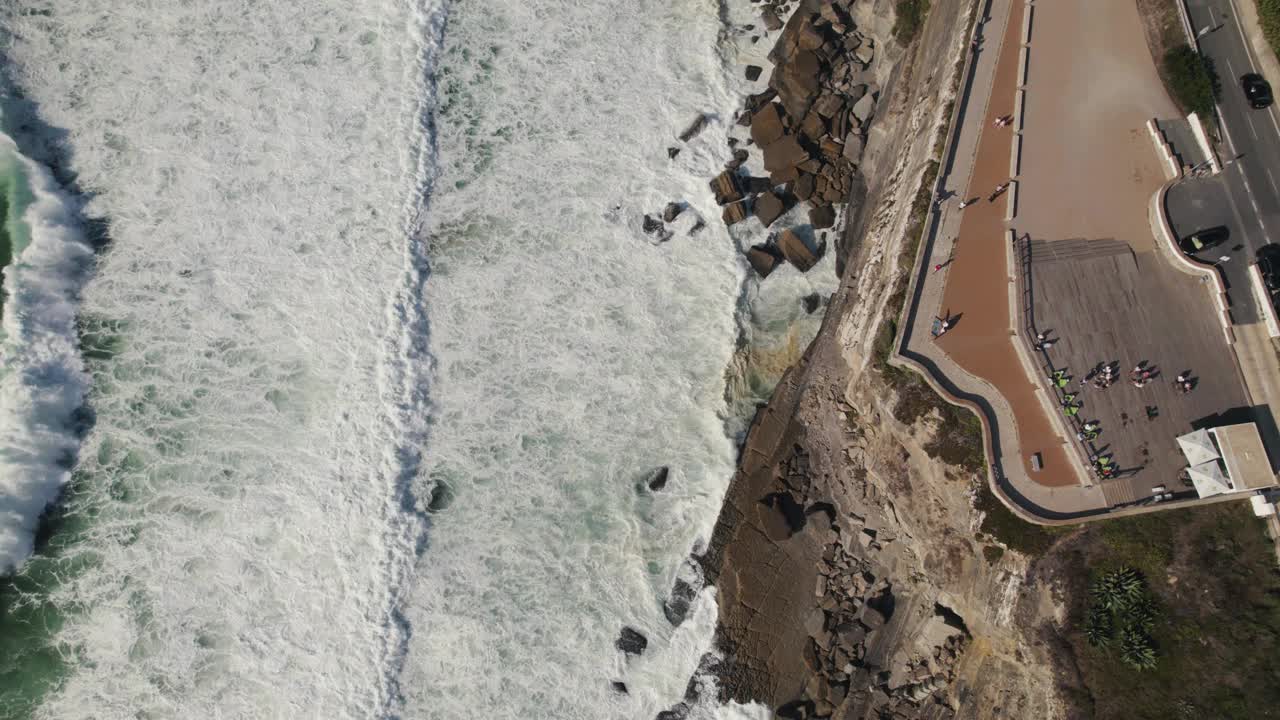 电影空中俯瞰多莉在镜头中的泡沫海浪击中海岸岩石悬崖。视频素材