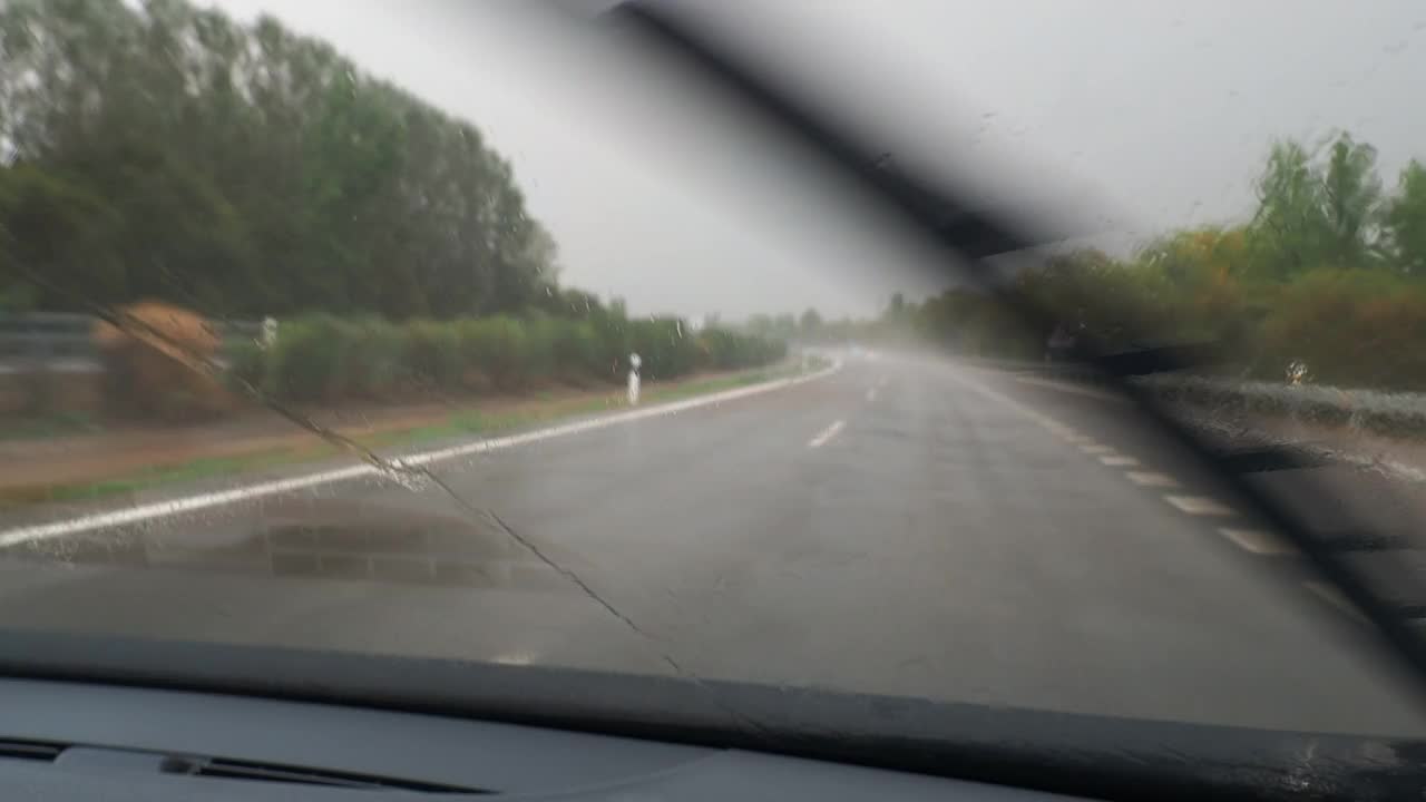 车的观点行驶在下雨的公路和挡风玻璃雨刷擦雨视频素材