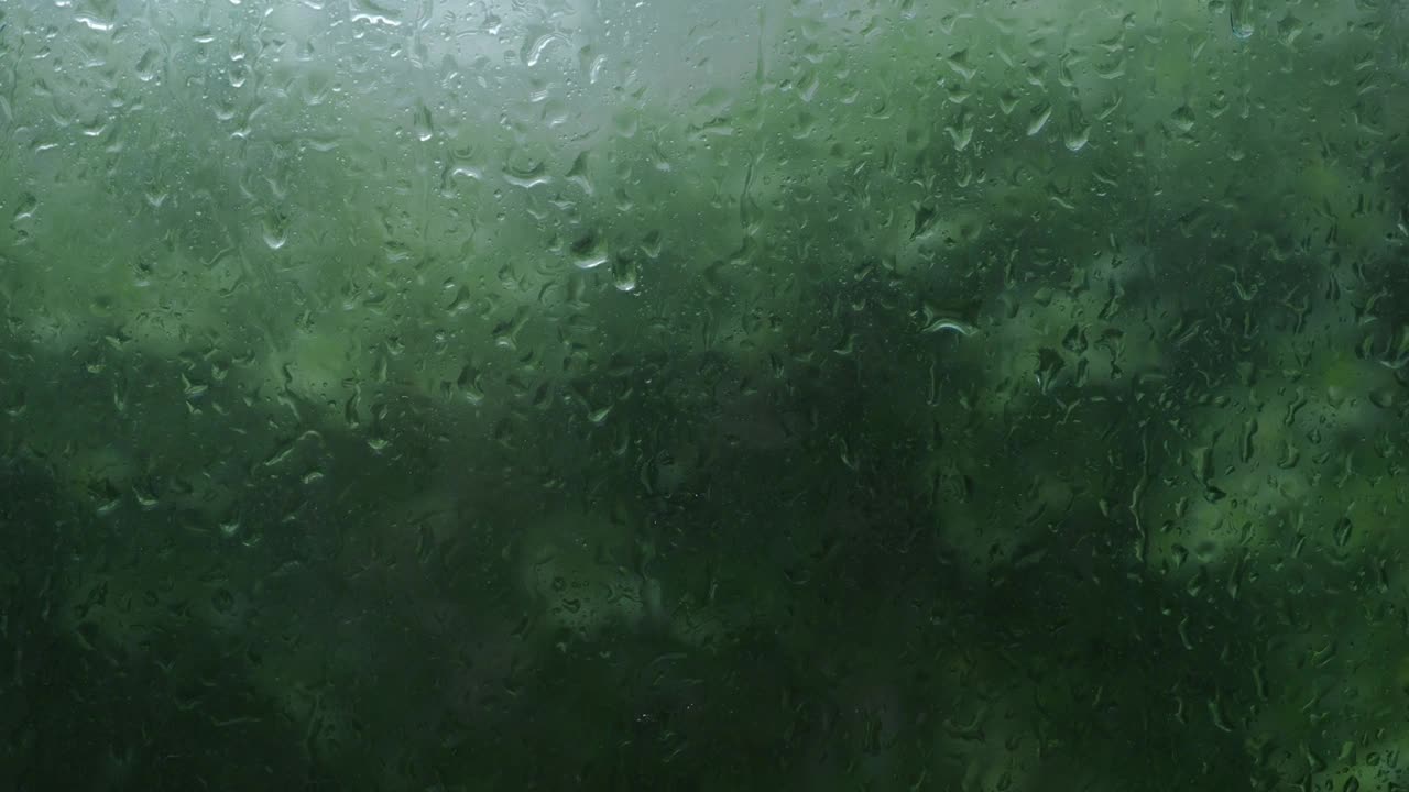 雨点落在窗户的下午。公寓或公寓客厅窗户花园在雨季。窗外模糊的雨，自然的树和天空。雨滴在窗口。风暴风的时刻。视频素材