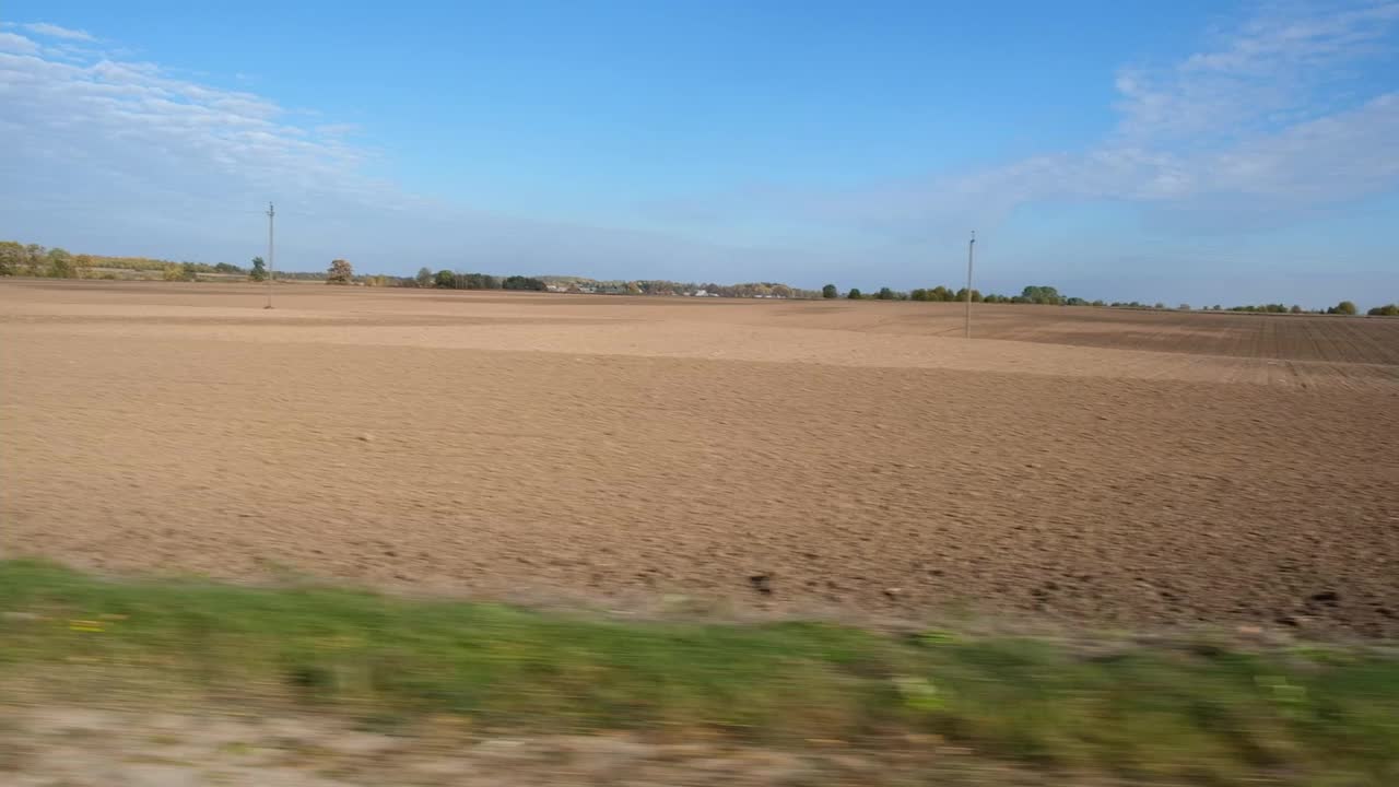 在穿过农田的路上超速行驶的汽车。通过汽车的侧窗在道路上运动。旅游与旅行，旅行与旅行的概念。美丽的秋天自然和风景。阳光明媚的天气。视频素材