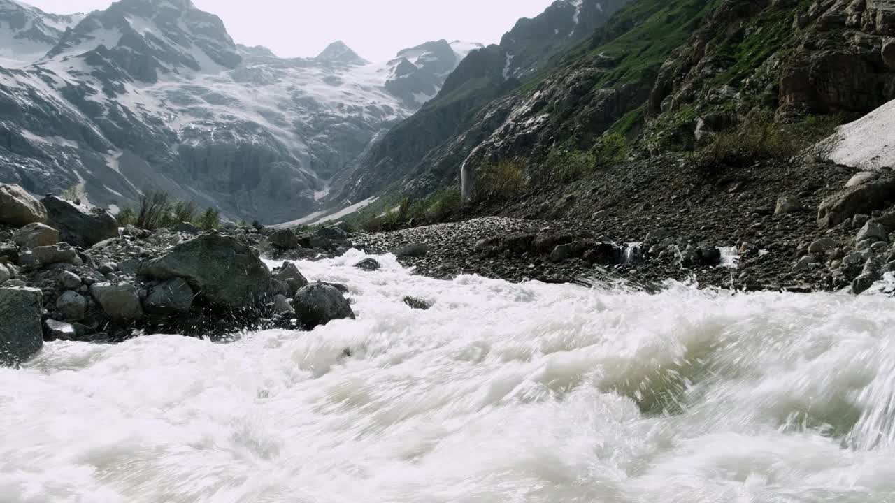 湍急的河流在落基山脉间流动，溅起了水花。雪在山上视频素材