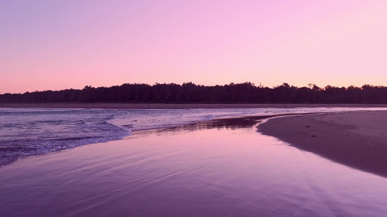 有趣的色彩和水流运动，波浪和倒影与海岸河口的水流相互作用，太阳刚刚落山时产生的强烈的粉红色辉光。视频素材