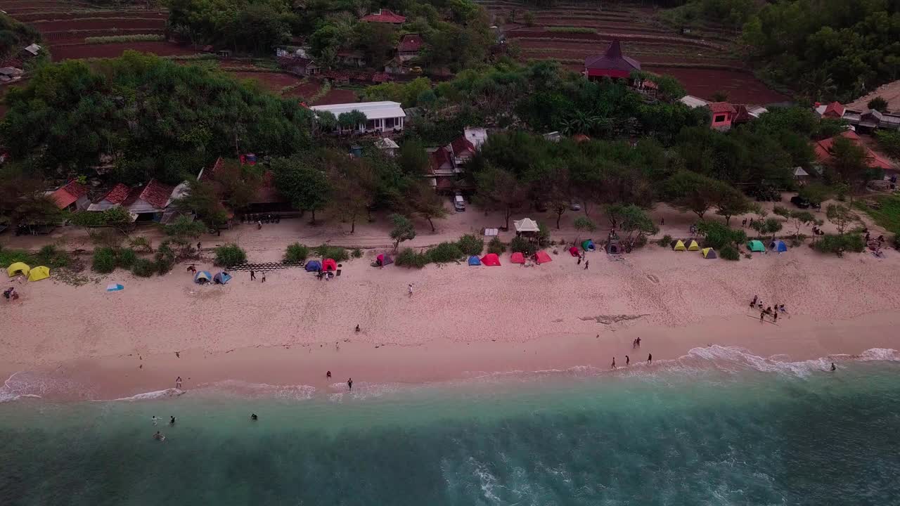 无人机拍摄的热带海滩上有白色的沙滩，人们在沙滩上玩耍，在海浪中玩耍视频素材