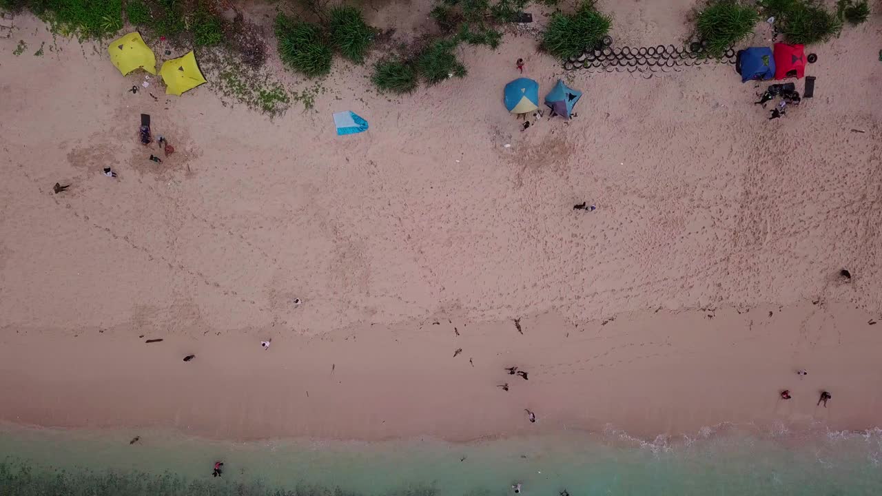 头顶上拍摄的热带海滩，白色的沙滩上，人们在沙滩上玩耍，在海浪中玩耍视频素材