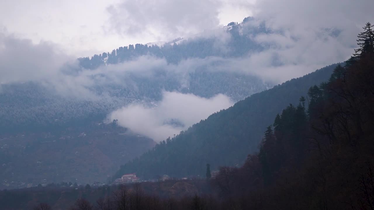 在印度喜马偕尔邦的马纳里，云朵在积雪覆盖的山上。在下雪的时候，山顶上的云。冬天的背景山被雪覆盖。视频素材