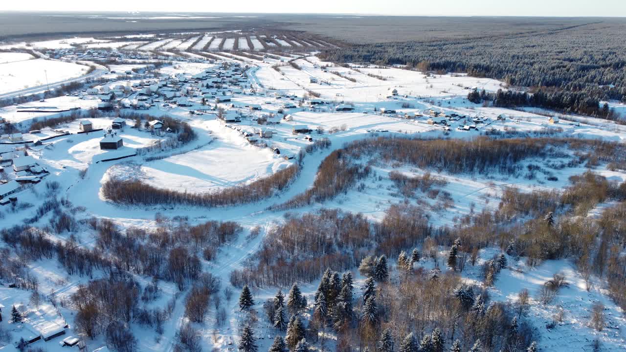 一个小村庄的无人机鸟瞰图，冬天的风景，寒冷的晴天，一切都被雪覆盖，4k视频与美丽的耀斑视频素材