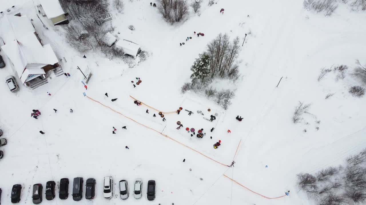 幸福的家庭在一个下雪的冬季公园里从山上下来，从无人机鸟瞰视频下载