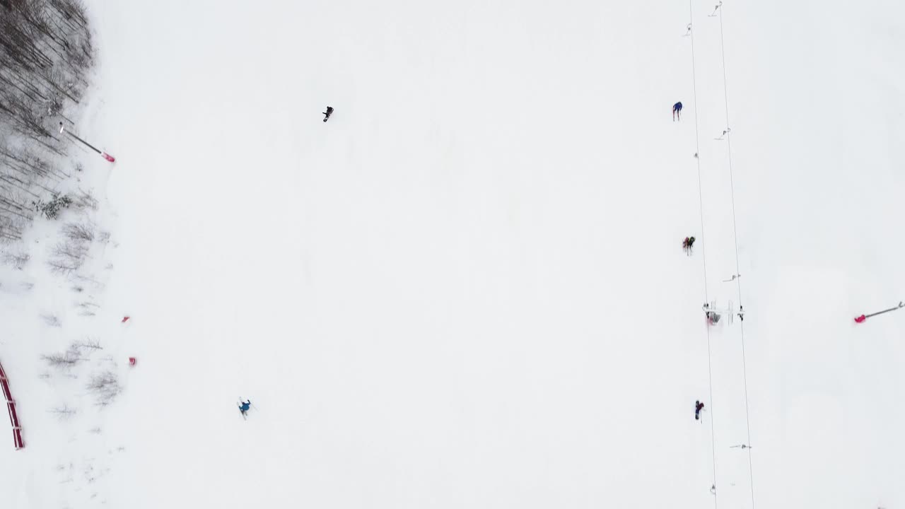 在滑雪胜地，无人机在索道上的全景俯视图。滑雪电梯运送滑雪者和滑雪板运动员在雪山度假村的冬季斜坡上，许多人。UHD 4 k的视频视频素材