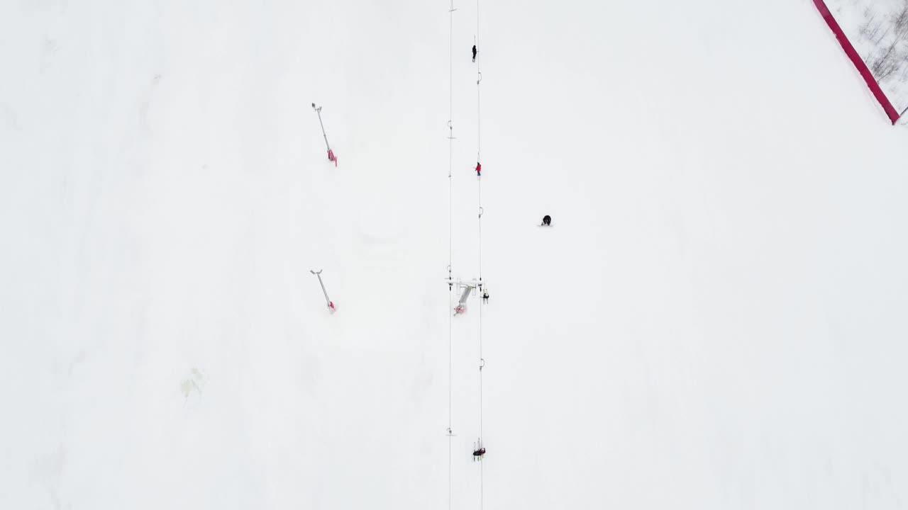 在滑雪胜地，无人机在索道上的全景俯视图。滑雪电梯运送滑雪者和滑雪板运动员在雪山度假村的冬季斜坡上，许多人。UHD 4 k的视频视频素材