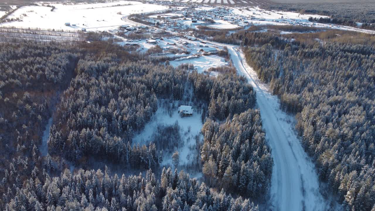 一个小村庄的无人机鸟瞰图，冬天的风景，寒冷的晴天，一切都被雪覆盖，4k视频与美丽的耀斑视频素材