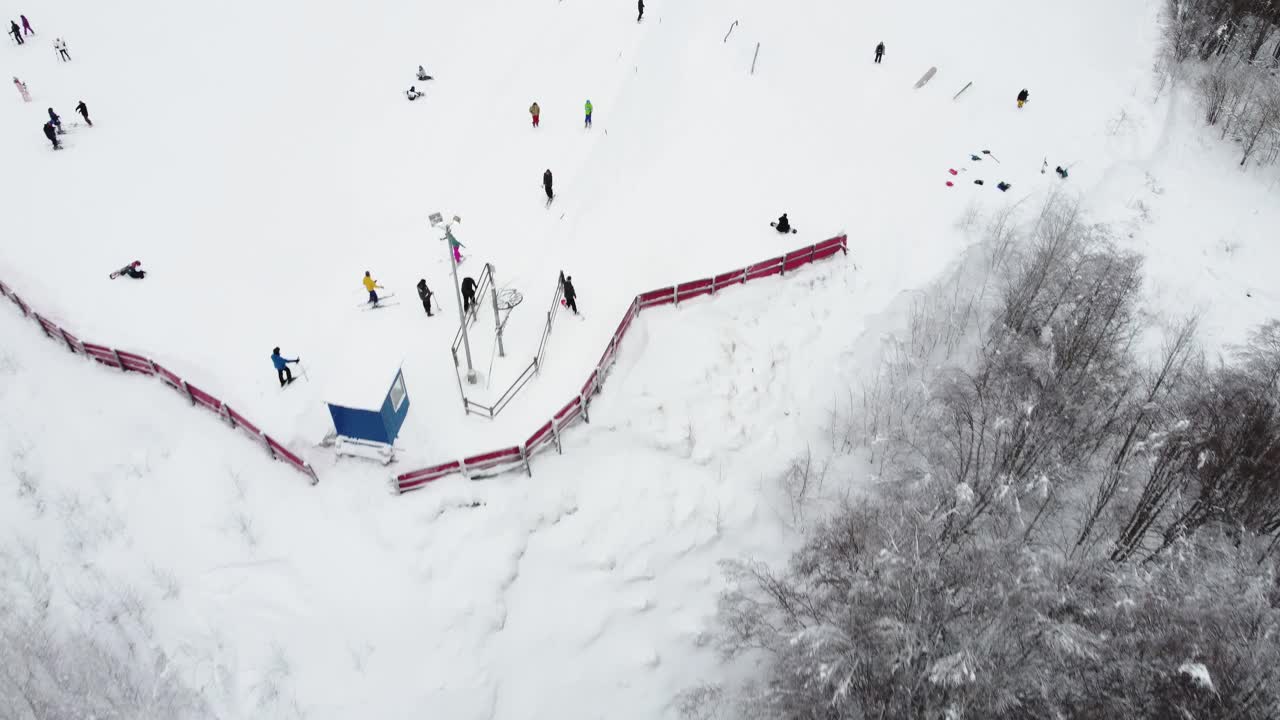 在滑雪胜地，无人机在索道上的全景俯视图。滑雪电梯运送滑雪者和滑雪板运动员在雪山度假村的冬季斜坡上，许多人。UHD 4 k的视频视频素材