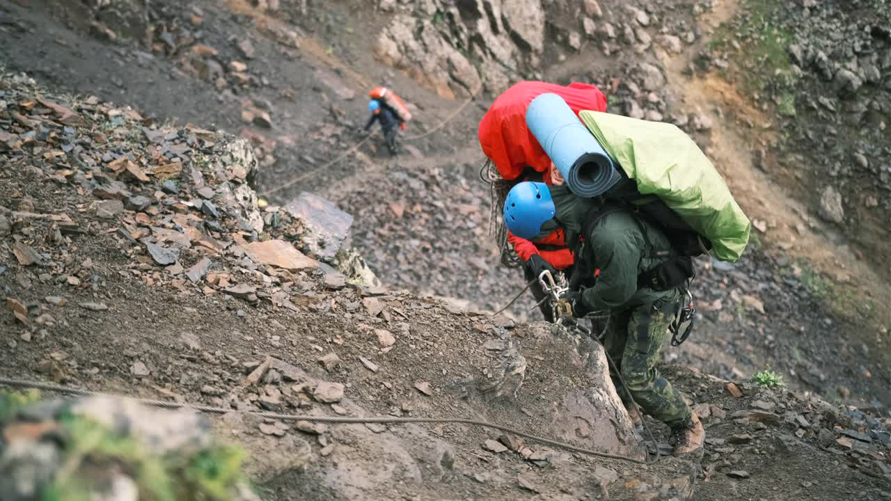 登山者在登山时，带着装备的大背包，在车站更换带保护绳的锁扣视频素材