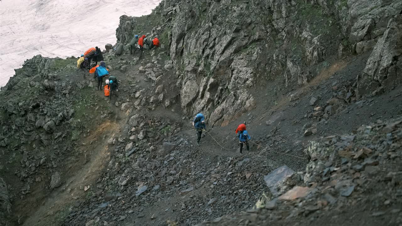 登山者抓住绳子在山上轮流行走。视频素材