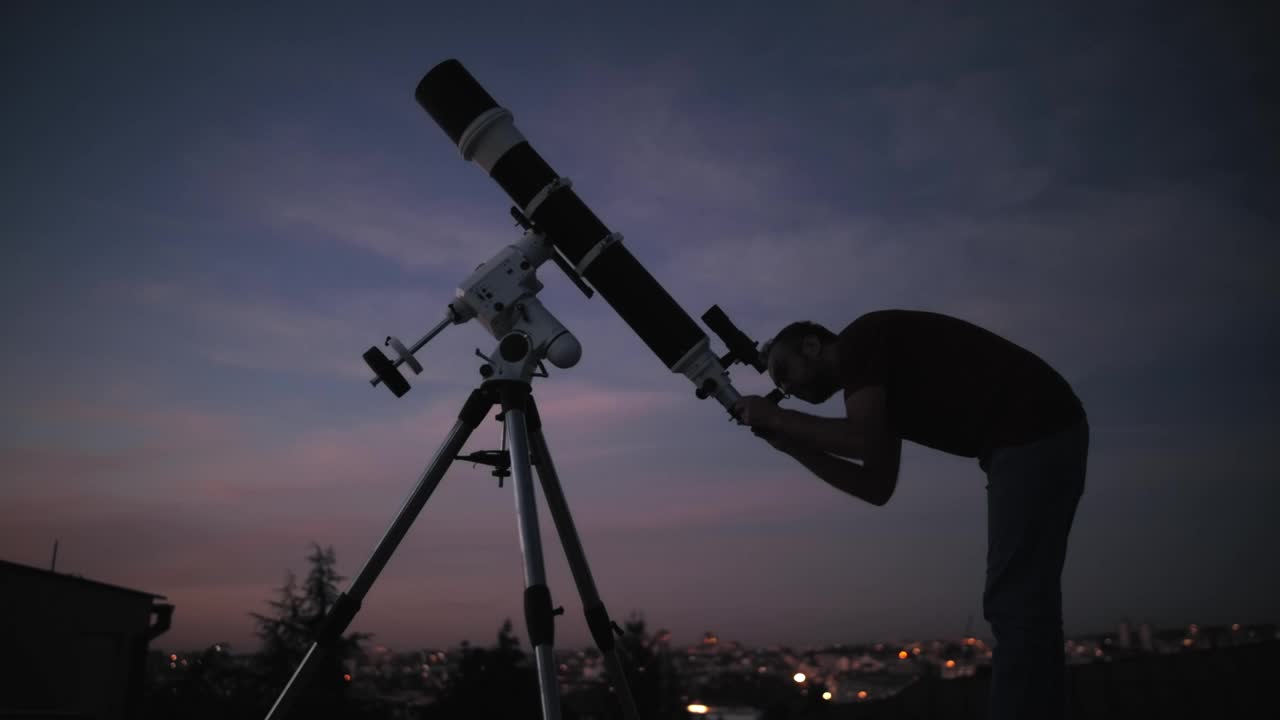 一个人的剪影，望远镜和星空下的乡村。视频素材