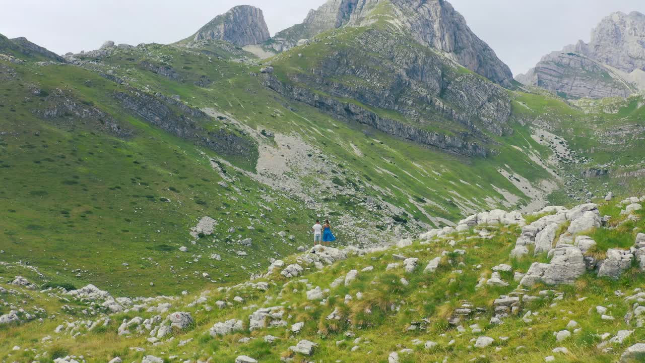 年轻的旅游夫妇的背面，手牵着手在岩石山顶享受美妙的全景。旅游、旅行和登山的概念。视频素材