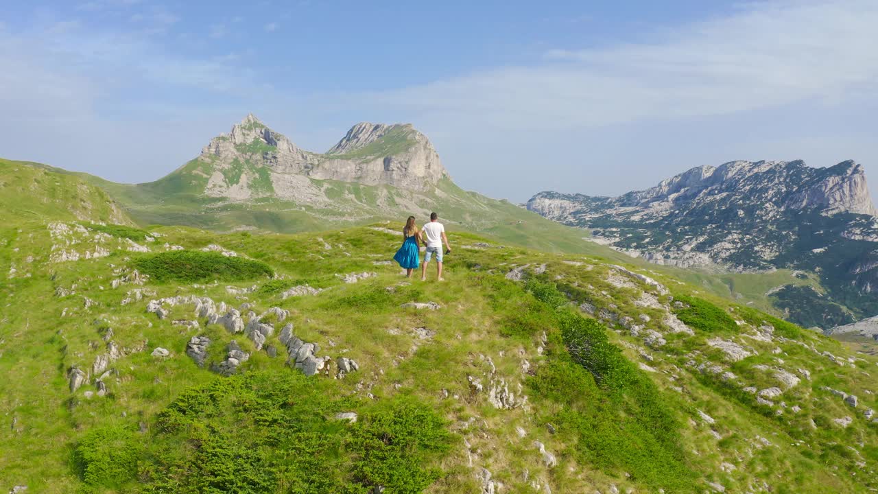 在黑山的杜米托，一对运动的年轻夫妇在他们活跃的春假期间在风景优美的山上徒步旅行。无人机视角4K。视频素材