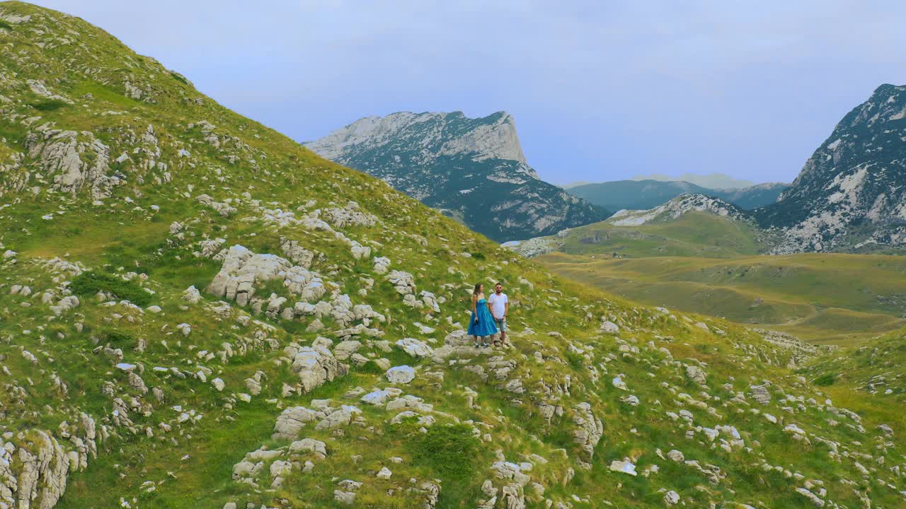 一对旅行者男人和女人在悬崖上放松的山和云的鸟瞰图，黑山。视频素材