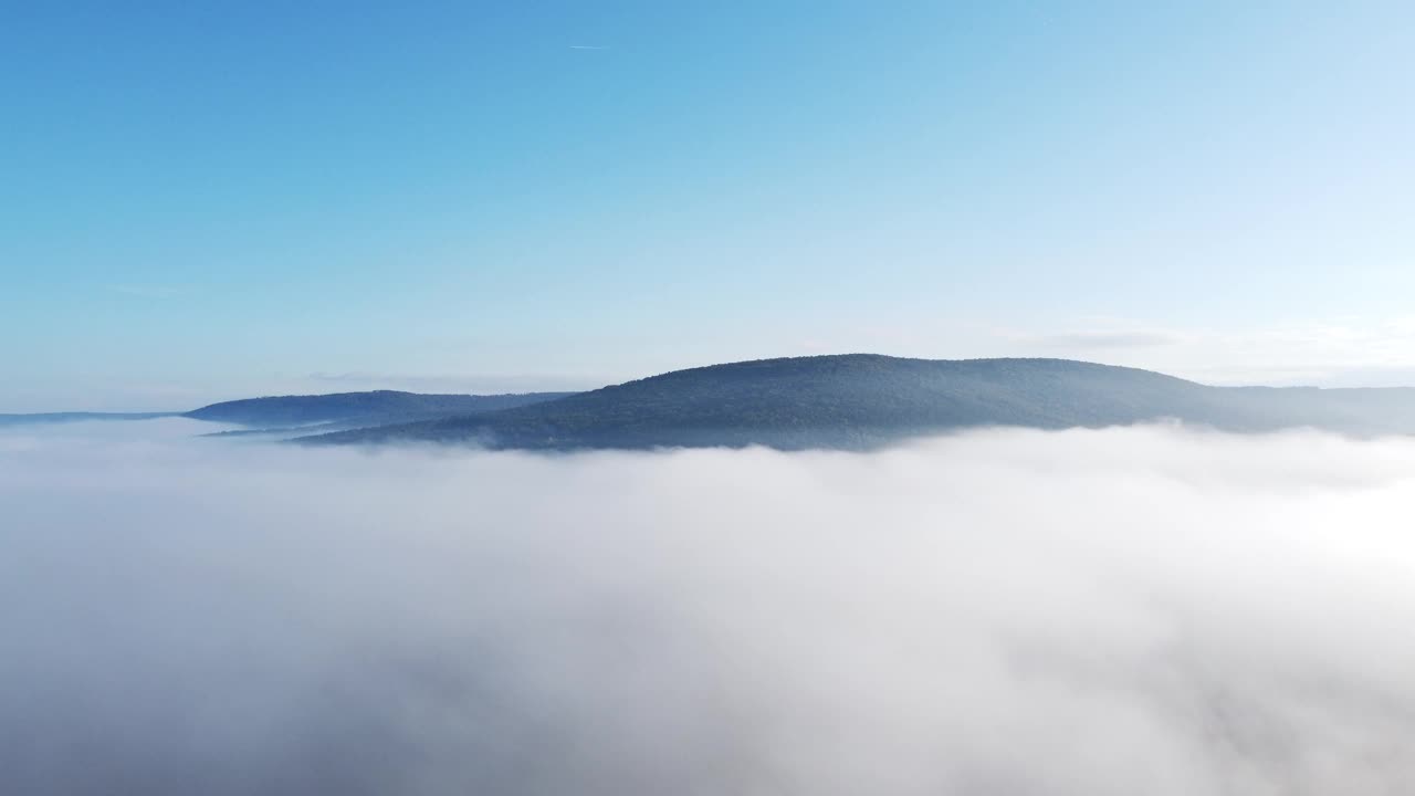 无人机在早晨突破秋天的雾，提供森林、山和天空的视图，鸟瞰图视频素材