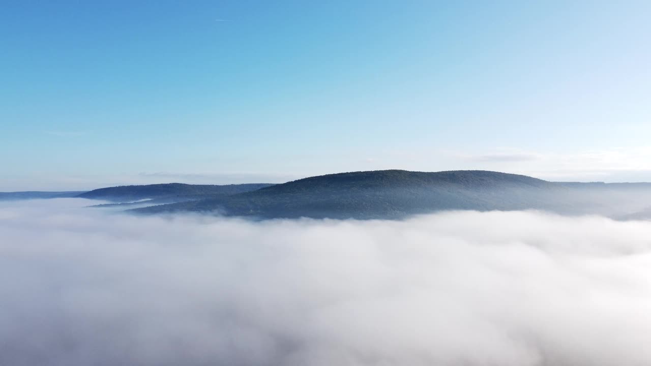 无人机在早晨突破秋天的雾，提供森林、山和天空的视图，鸟瞰图视频素材