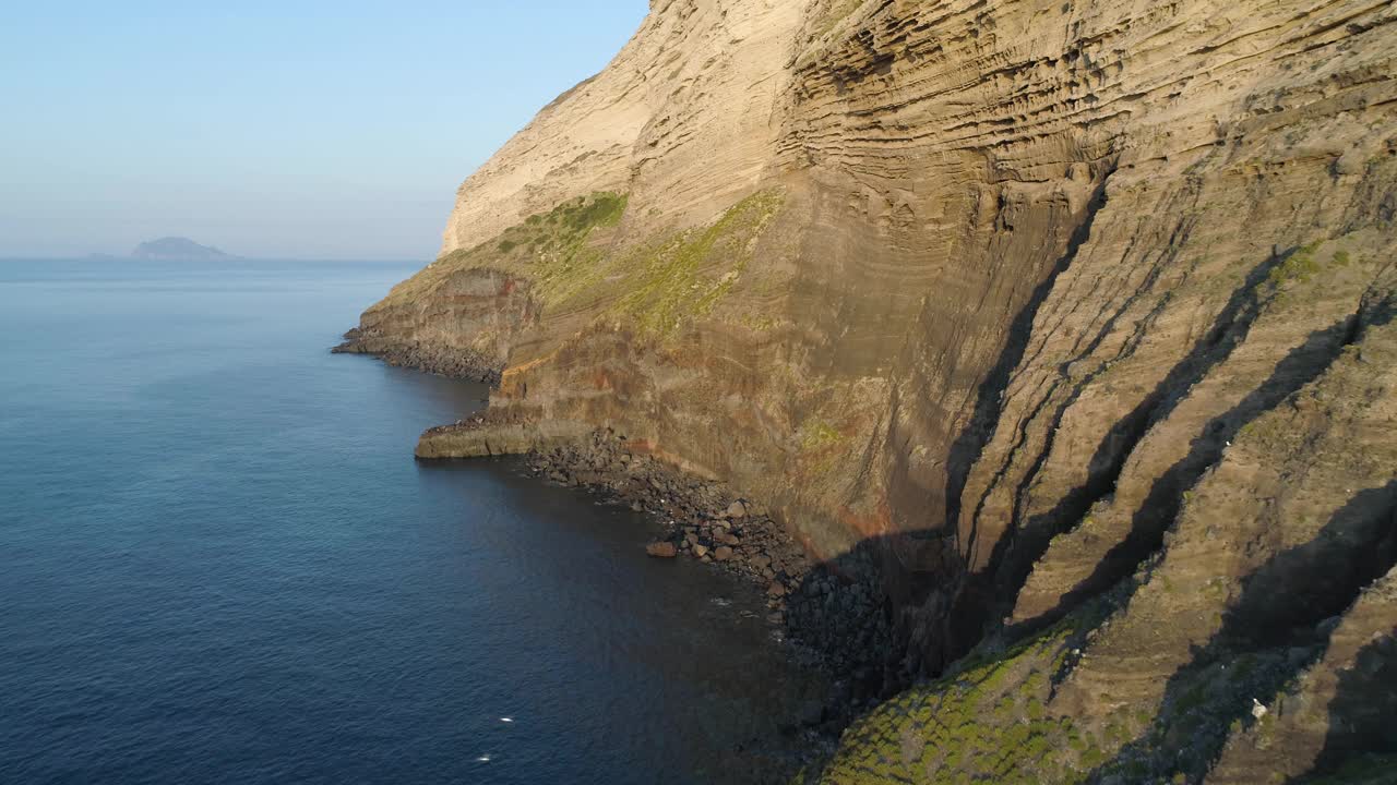 盐湖城海岸鸟瞰图。夏日落日下的巨大悬崖。山坡上的绿树丛，山谷里的小村庄。背景是蓝色的天空视频素材