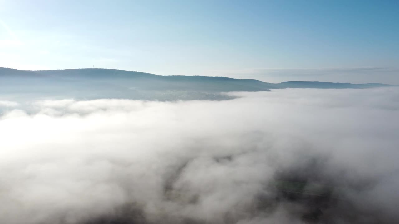 无人机在早晨突破秋天的雾，提供森林、山和天空的视图，鸟瞰图视频素材