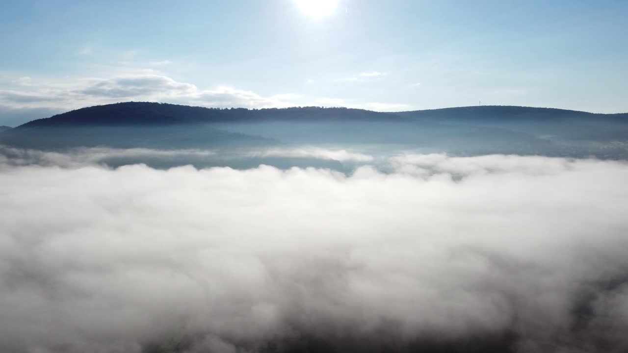 无人机在早晨突破秋天的雾，提供森林、山和天空的视图，鸟瞰图视频素材