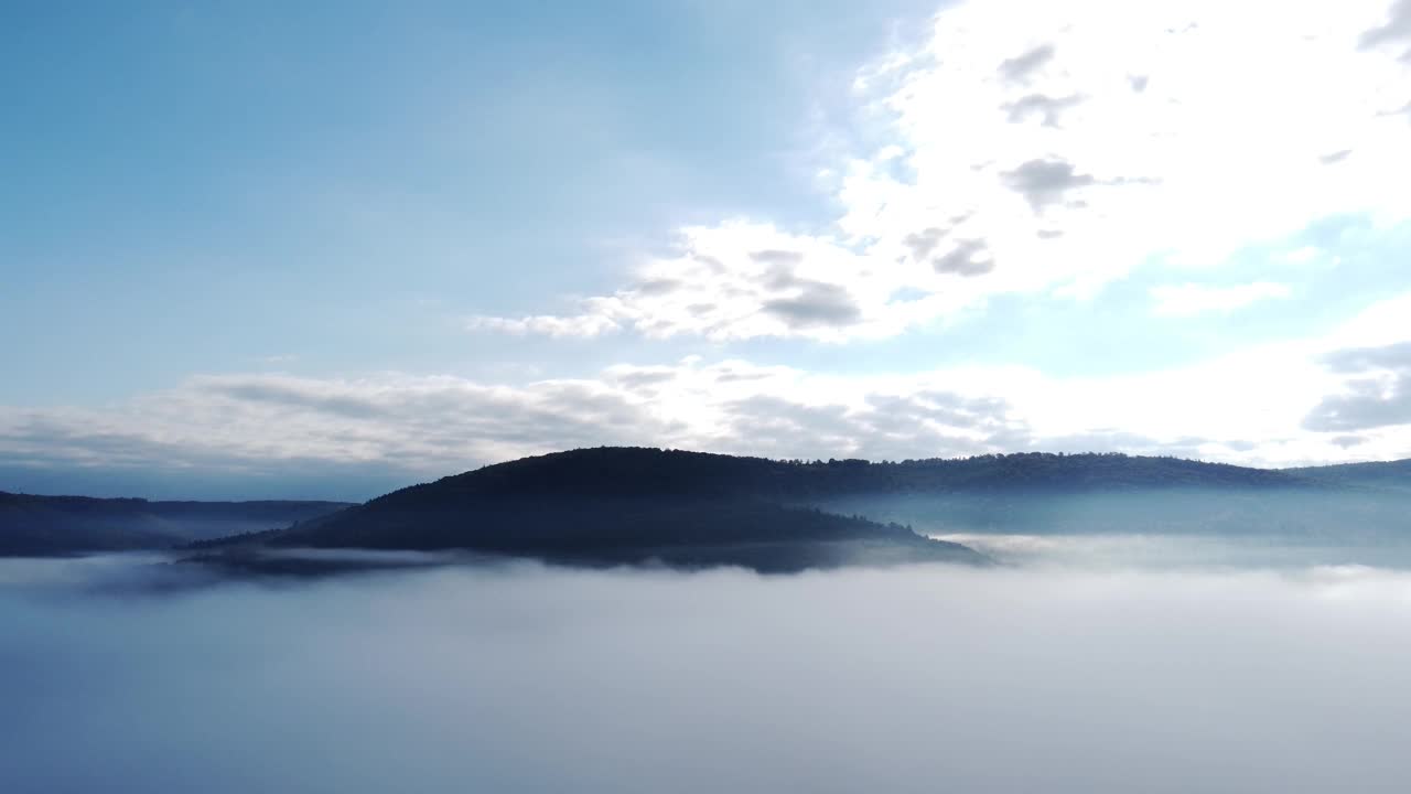 无人机在早晨突破秋天的雾，提供森林、山和天空的视图，鸟瞰图视频素材