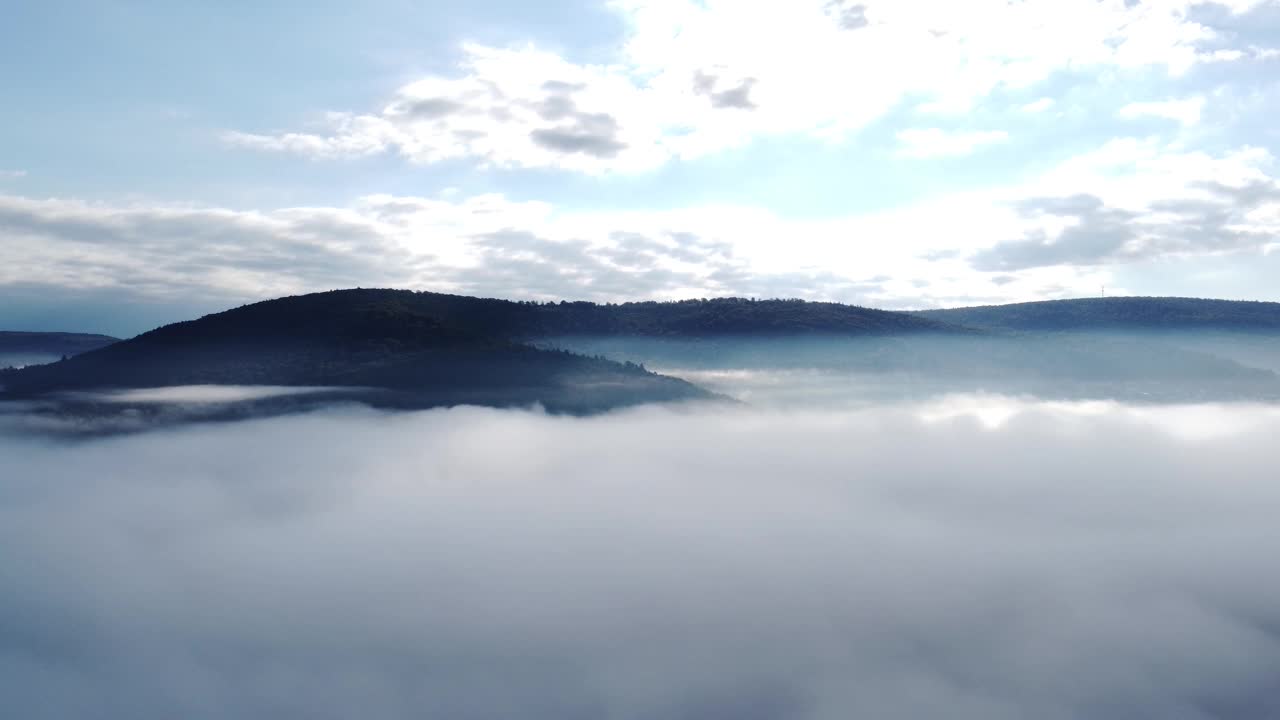 无人机在早晨突破秋天的雾，提供森林、山和天空的视图，鸟瞰图视频素材