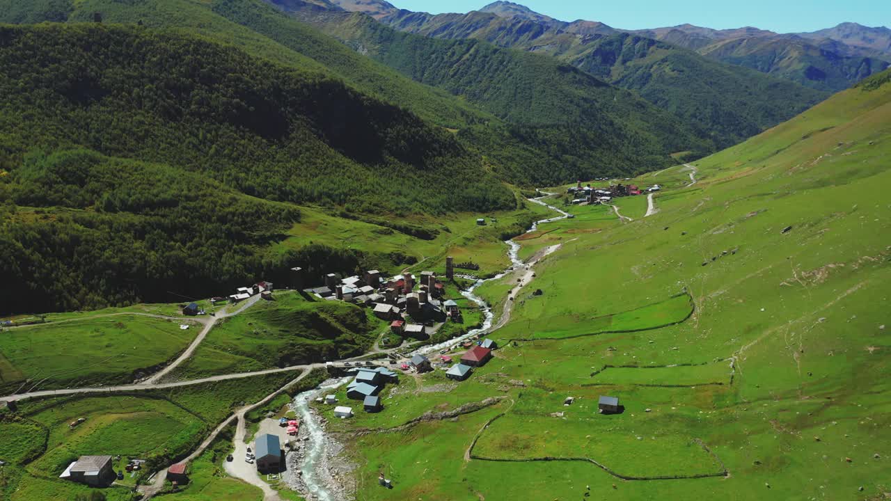 在一个阳光明媚的夏日，沿着河边的山村鸟瞰图。视频素材