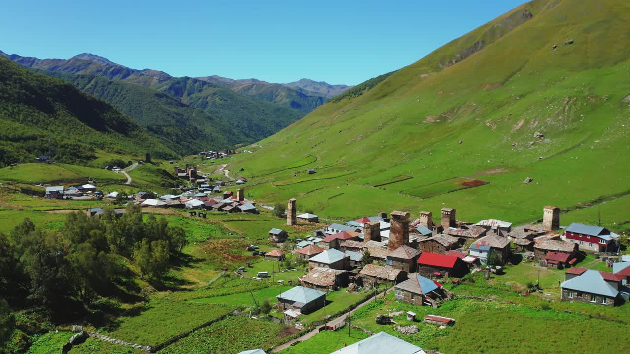 在一个阳光明媚的日子，沿着河边的山村鸟瞰图。视频素材