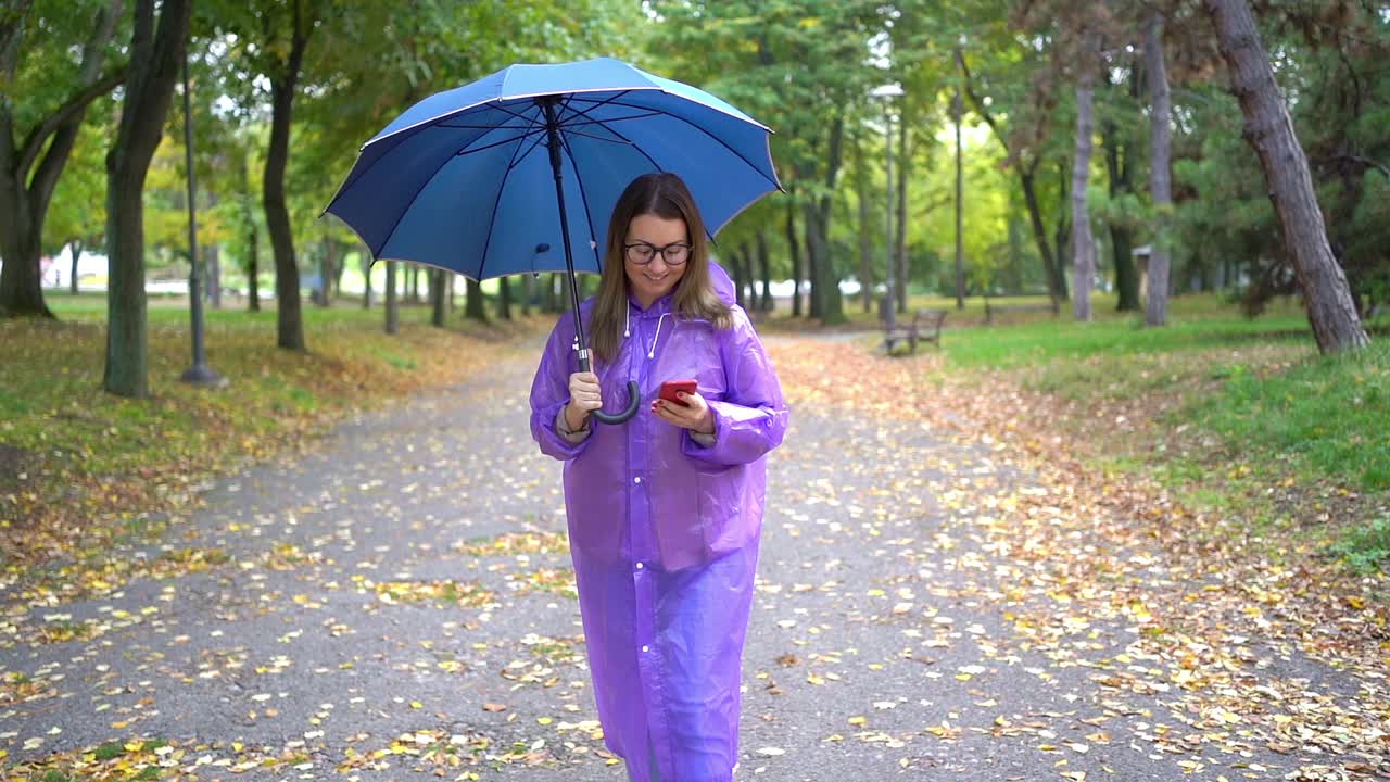 女人在雨中使用智能手机视频素材