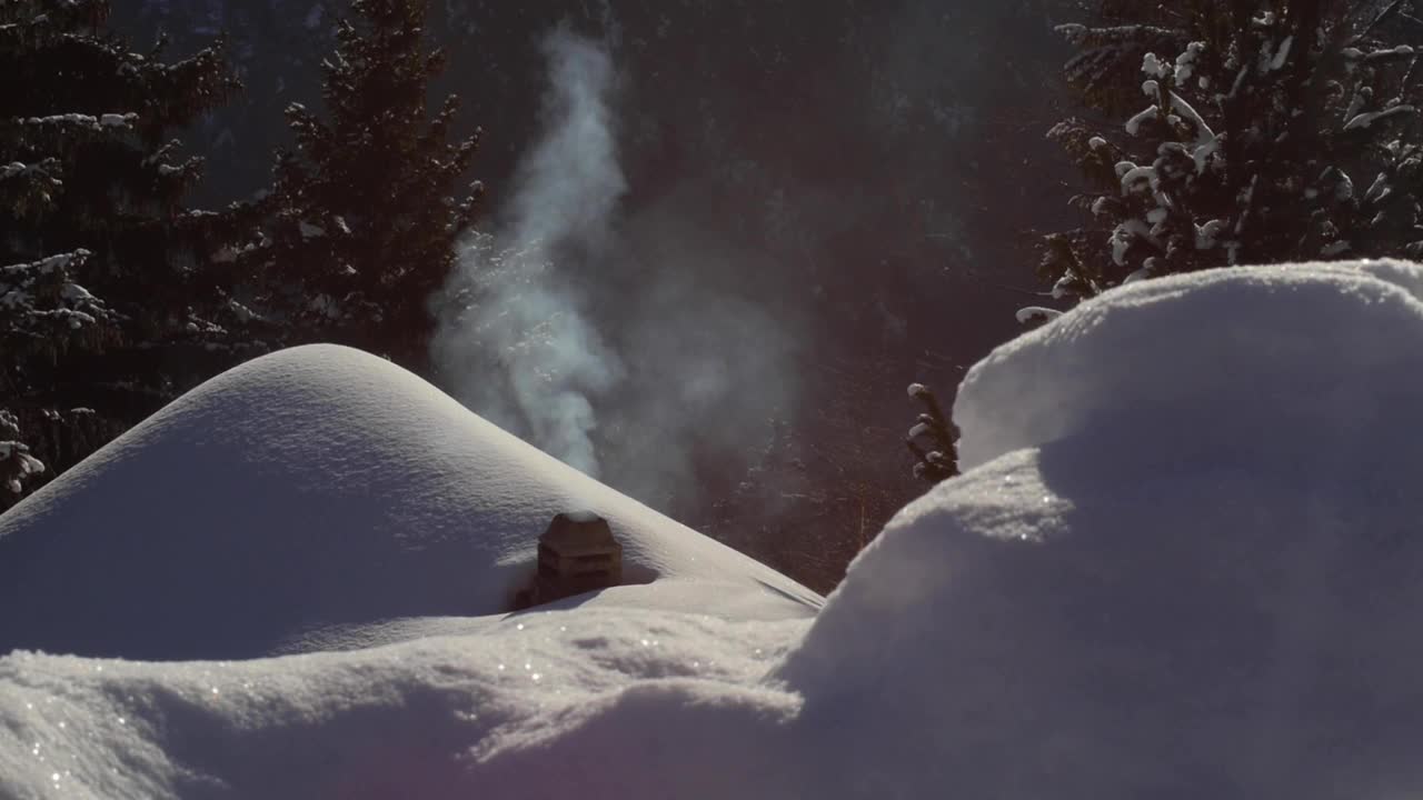 穆迪拍到了一个冒烟的烟囱。屋顶上有雪的小屋。冬天。视频素材