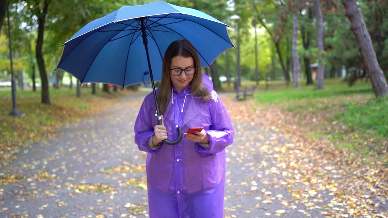 女人在雨中使用智能手机视频素材