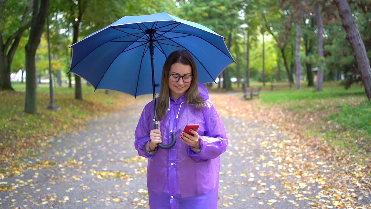 女人在雨中使用智能手机视频素材