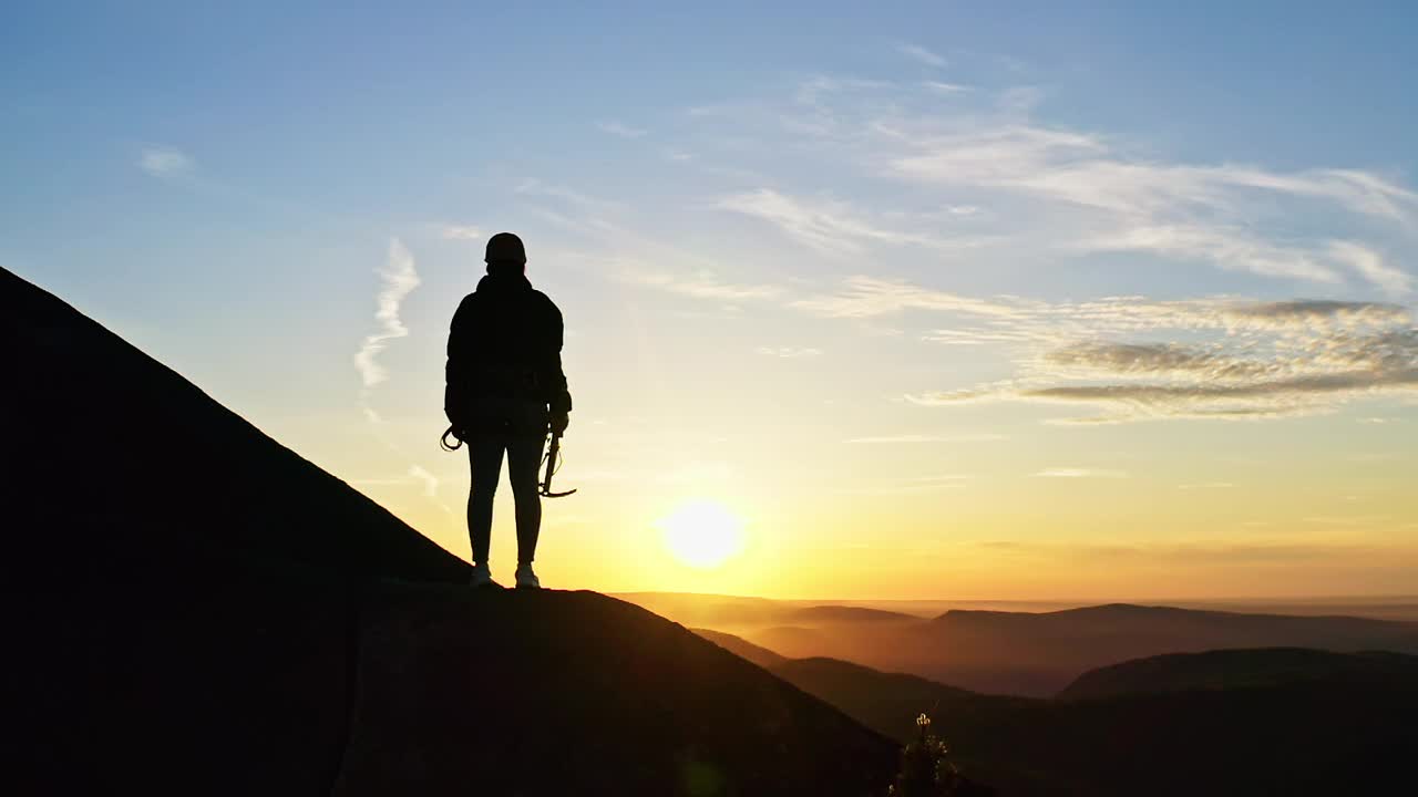 一位女登山者站在山坡上举起冰镐的慢动作。视频素材