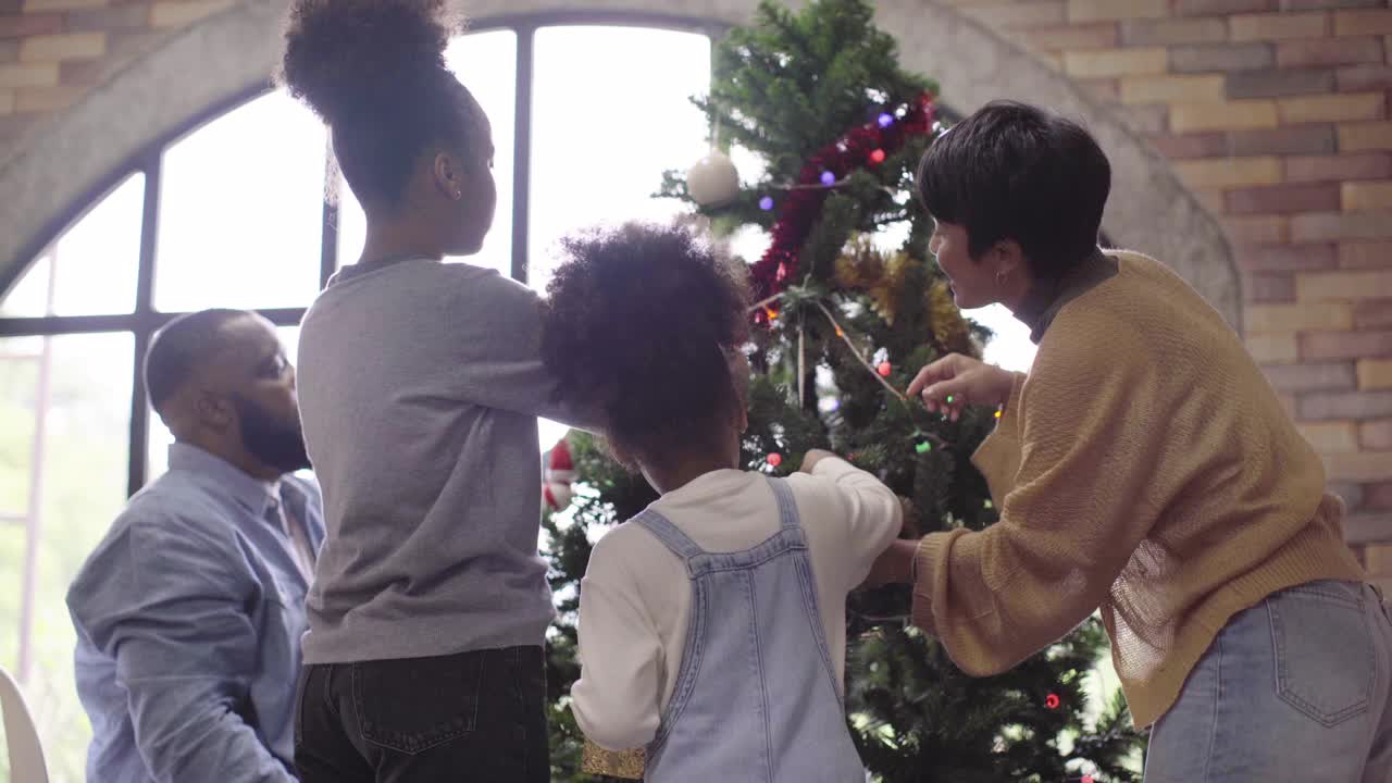 非裔美国家庭在公寓里一起装饰圣诞树视频素材