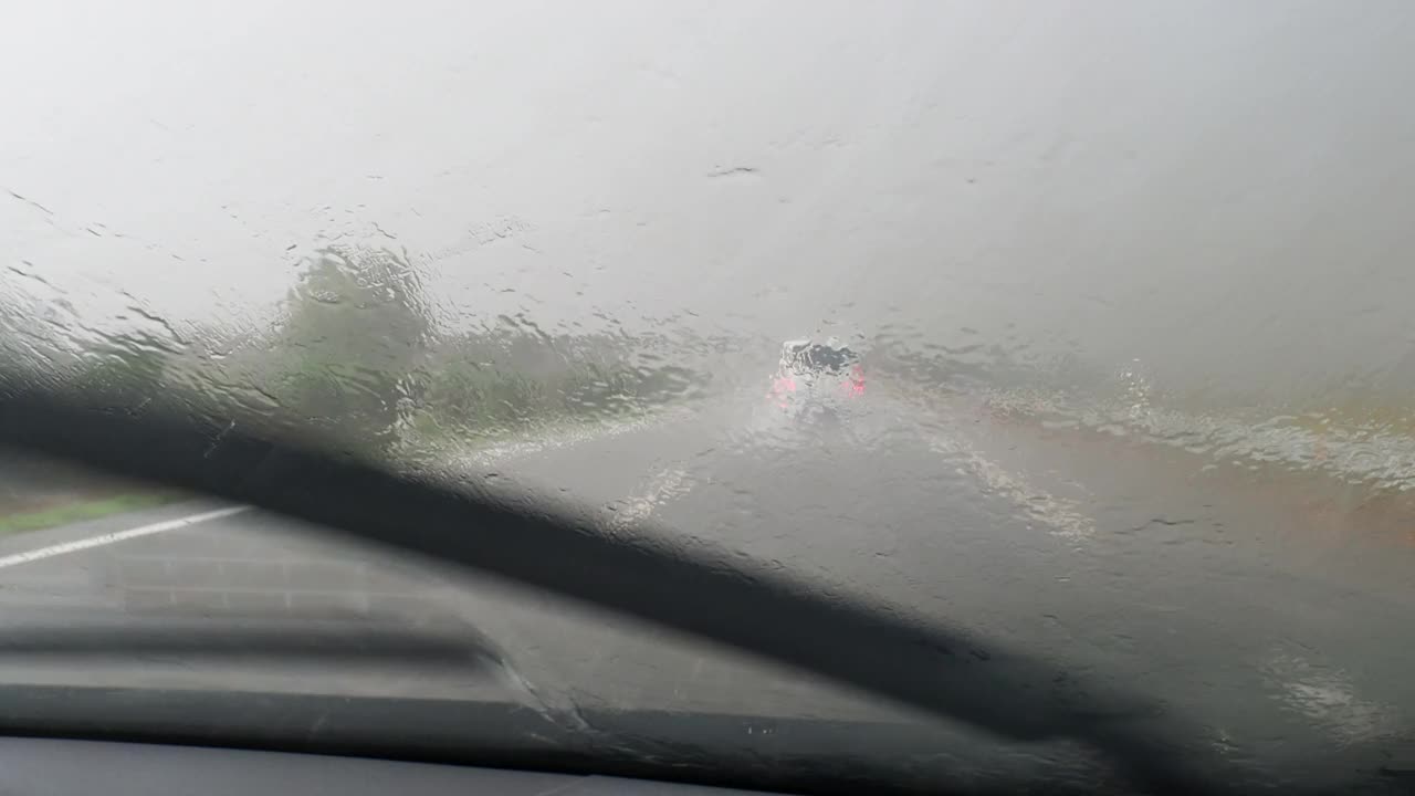 车的观点行驶在下雨的公路和挡风玻璃雨刷擦雨视频素材