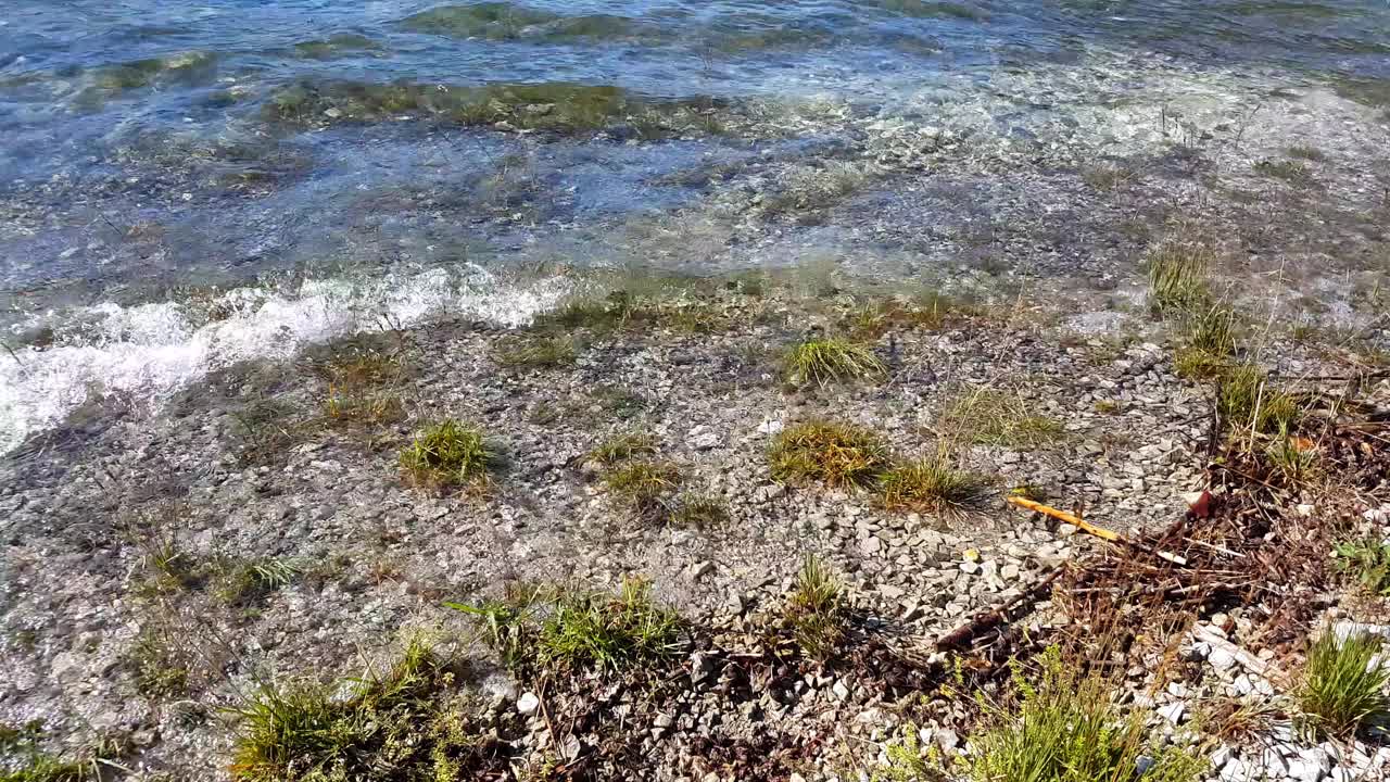 特写镜头:清澈的海浪覆盖着湖岸的碎石视频素材