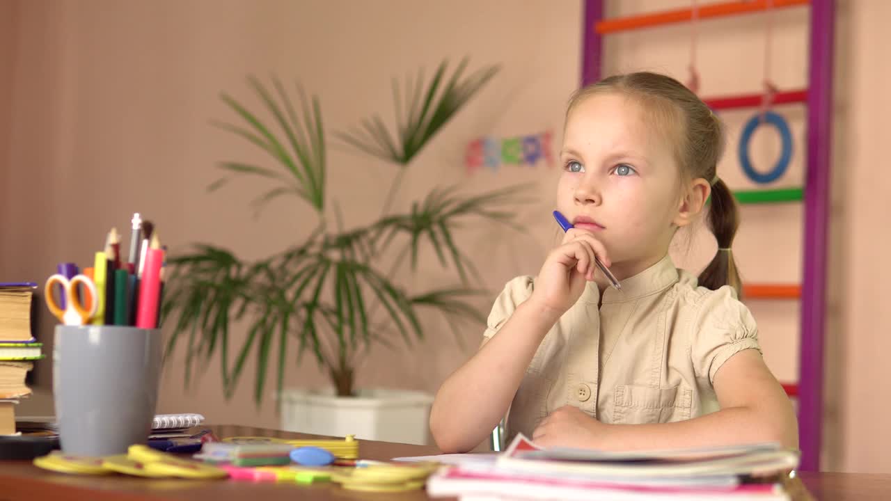 学龄前儿童坐在桌子旁思考。她做家庭作业视频素材