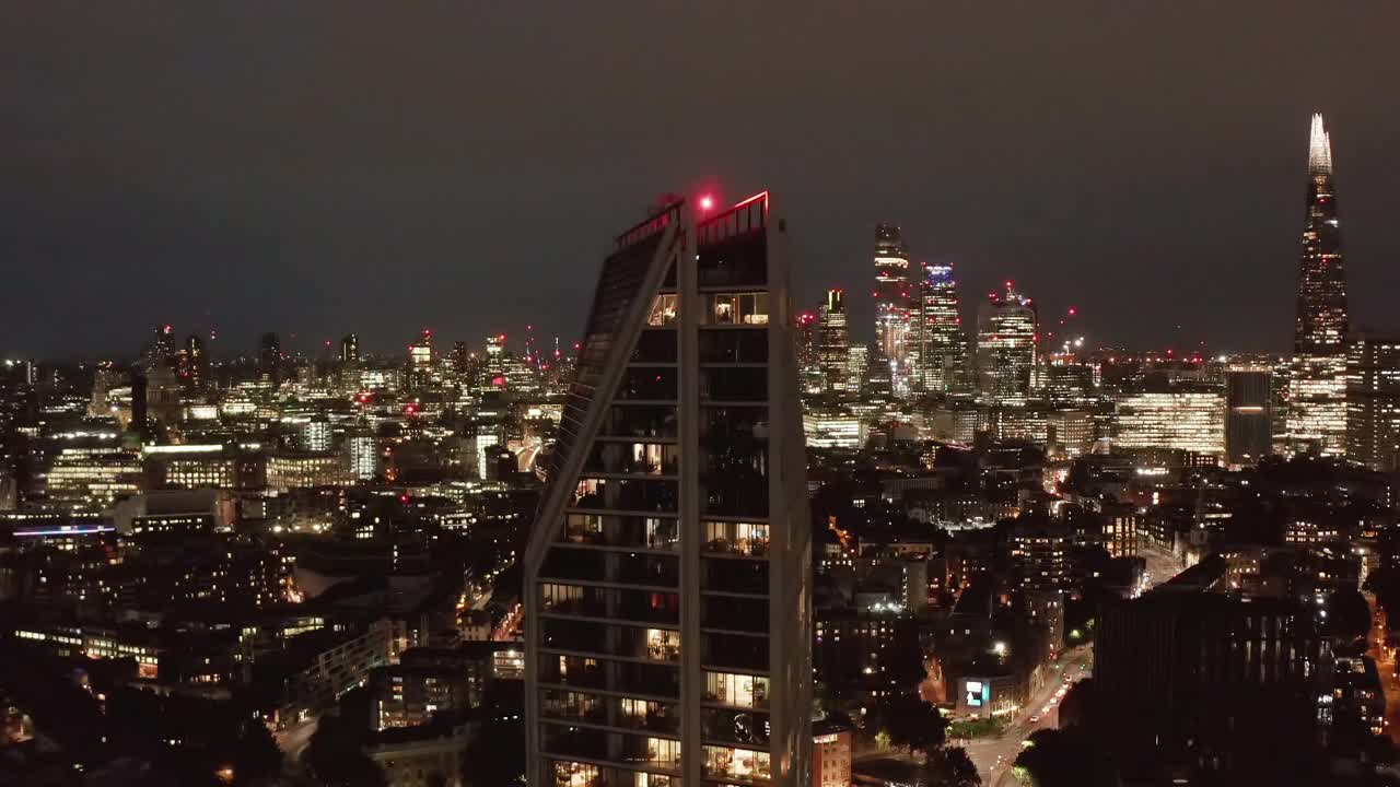 现代高层公寓塔楼顶部升起的镜头。风景优美的夜市与市中心摩天大楼的背景。英国伦敦视频素材