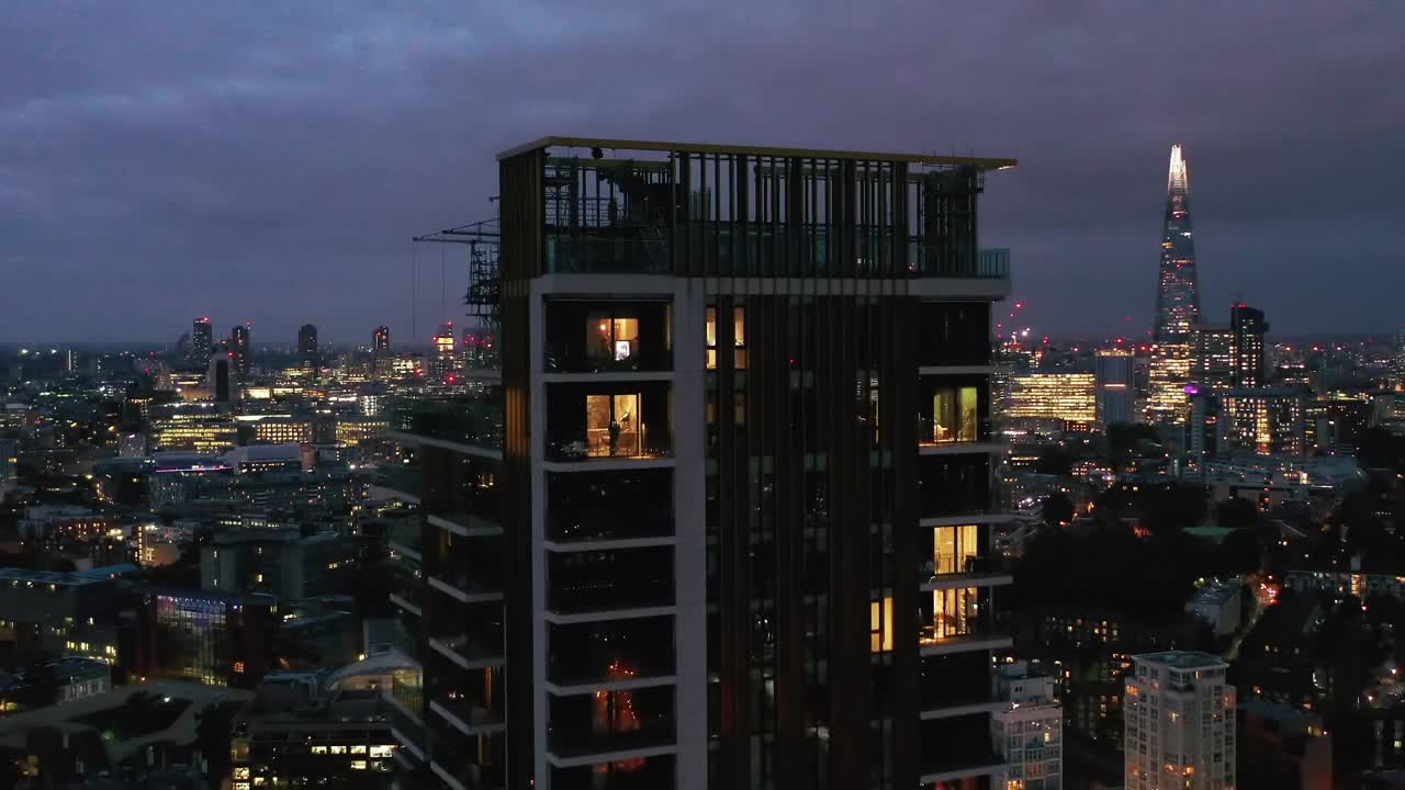 飞越高层住宅楼顶露台。市中心摩天大楼的夜景一览无遗。英国伦敦视频素材