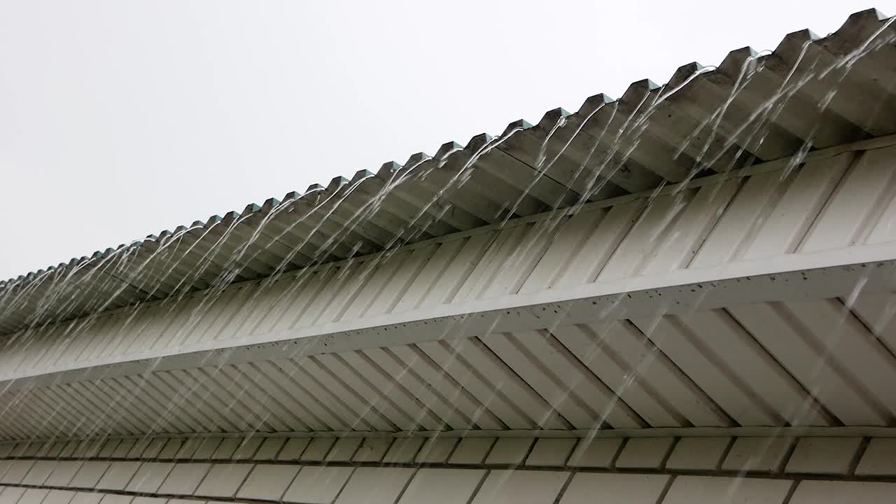 一股强烈的雨水从屋顶流下来。雨水从乡村住宅的屋顶漏出。下雨的天空。排水系统。有选择性的重点视频素材