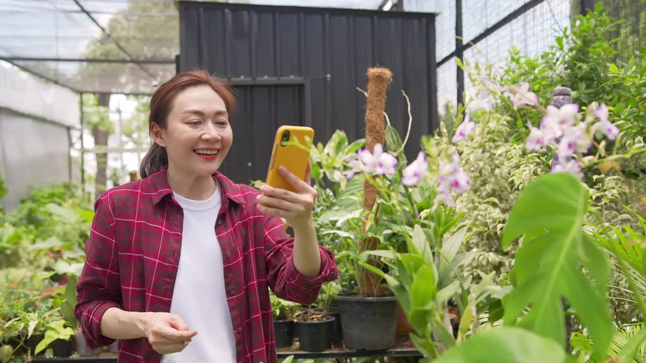 4K亚洲女植物商店老板在智能手机上直播盆栽为在线商店视频素材