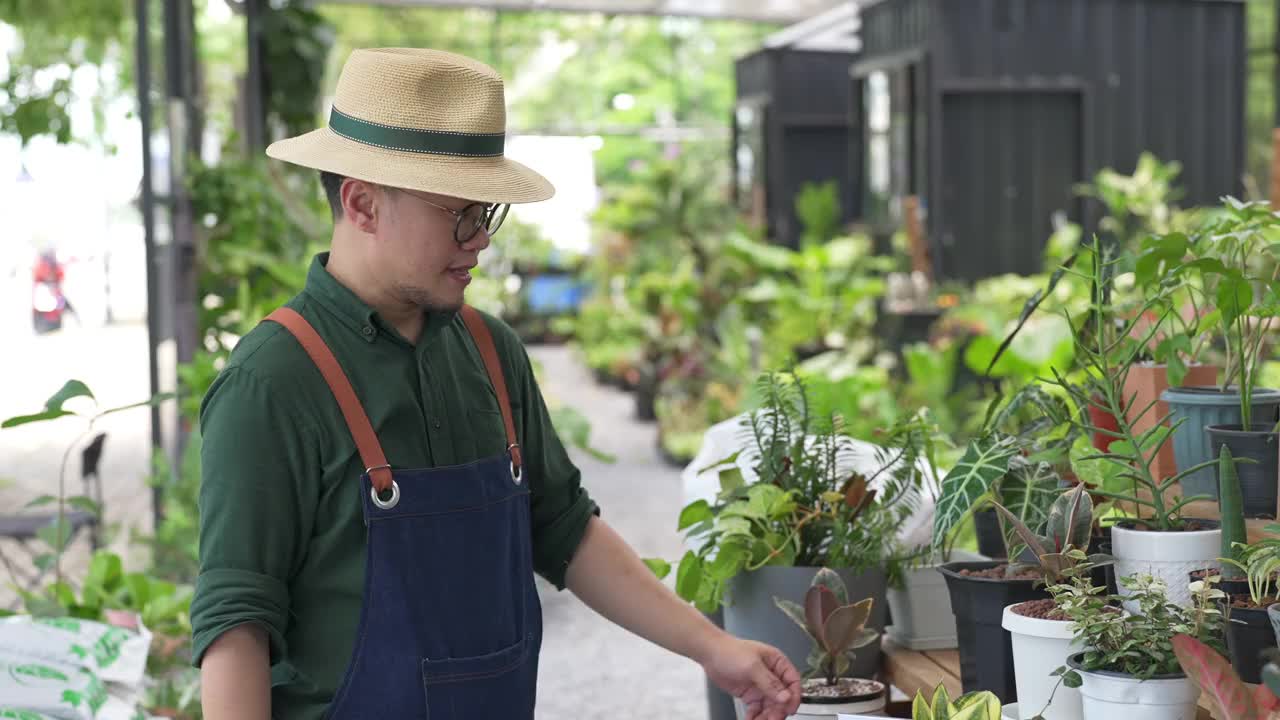 4K亚洲男人植物商店老板照顾植物和花卉在温室花园。视频素材