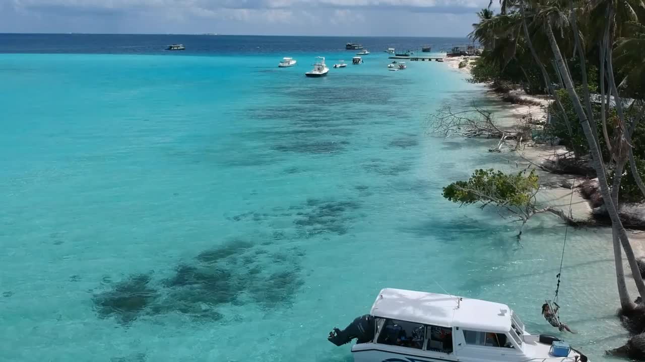 热带海滩的风景。美丽的海浪，绿色的棕榈树，蓝色的水和天空的马尔代夫视频下载