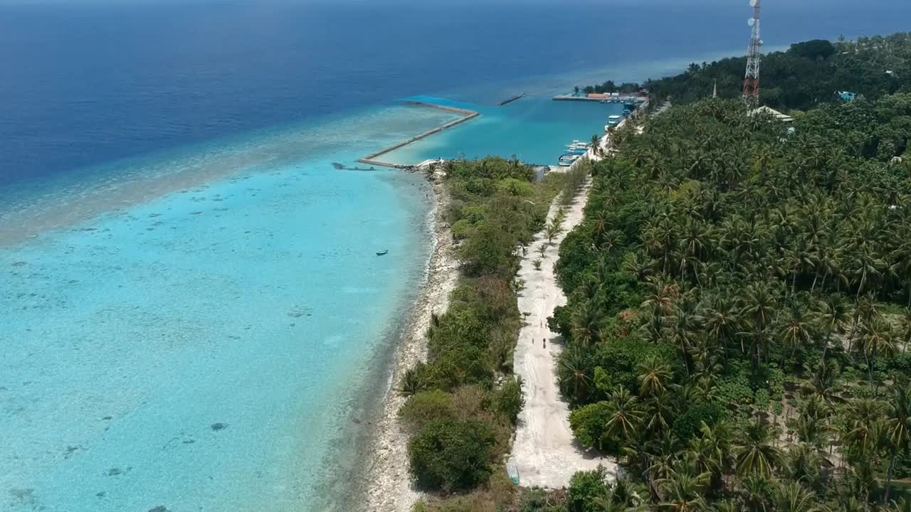 热带海滩的风景。美丽的海浪，绿色的棕榈树，蓝色的水和天空的马尔代夫视频下载