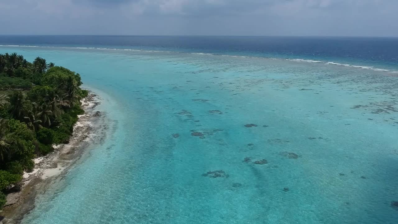 热带海滩的风景。美丽的海浪，绿色的棕榈树，蓝色的水和天空的马尔代夫视频素材