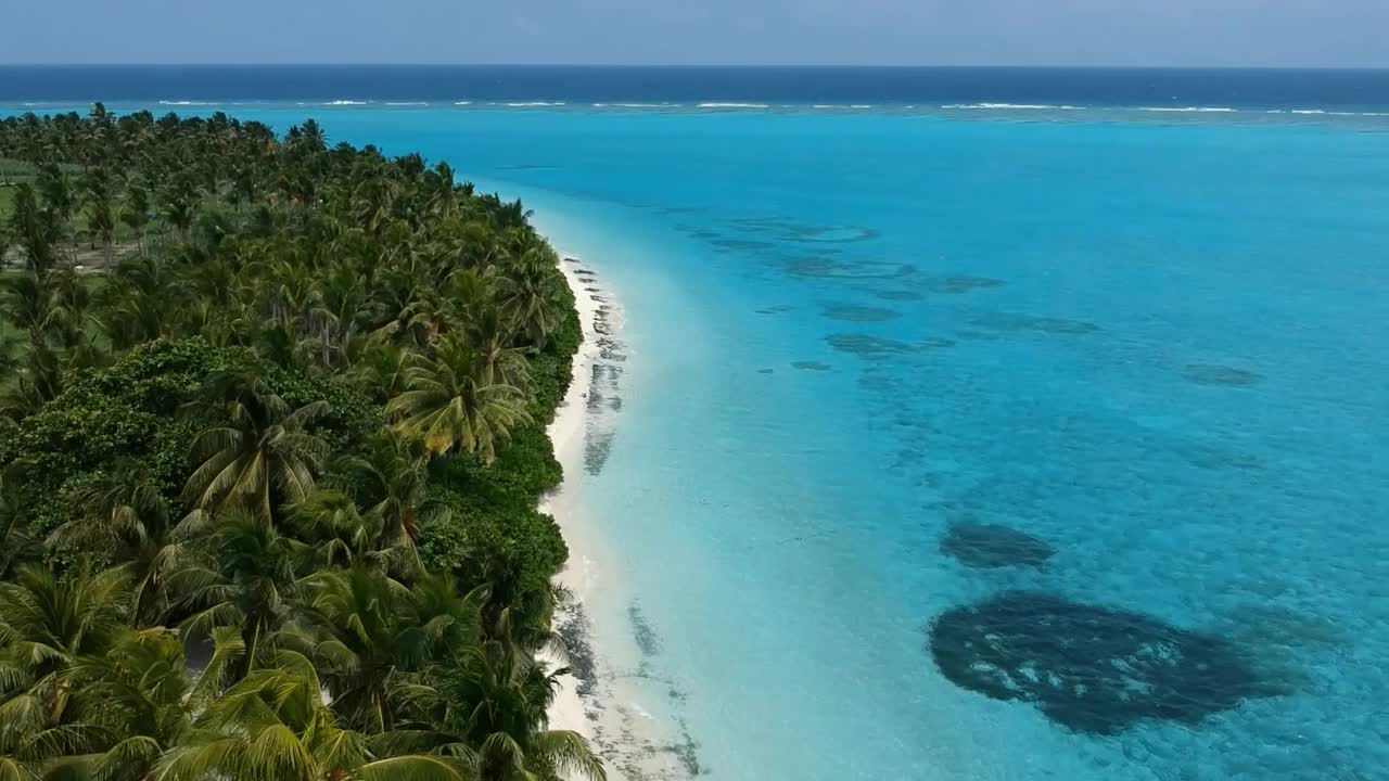 热带海滩的风景。美丽的海浪，绿色的棕榈树，蓝色的水和天空的马尔代夫视频下载