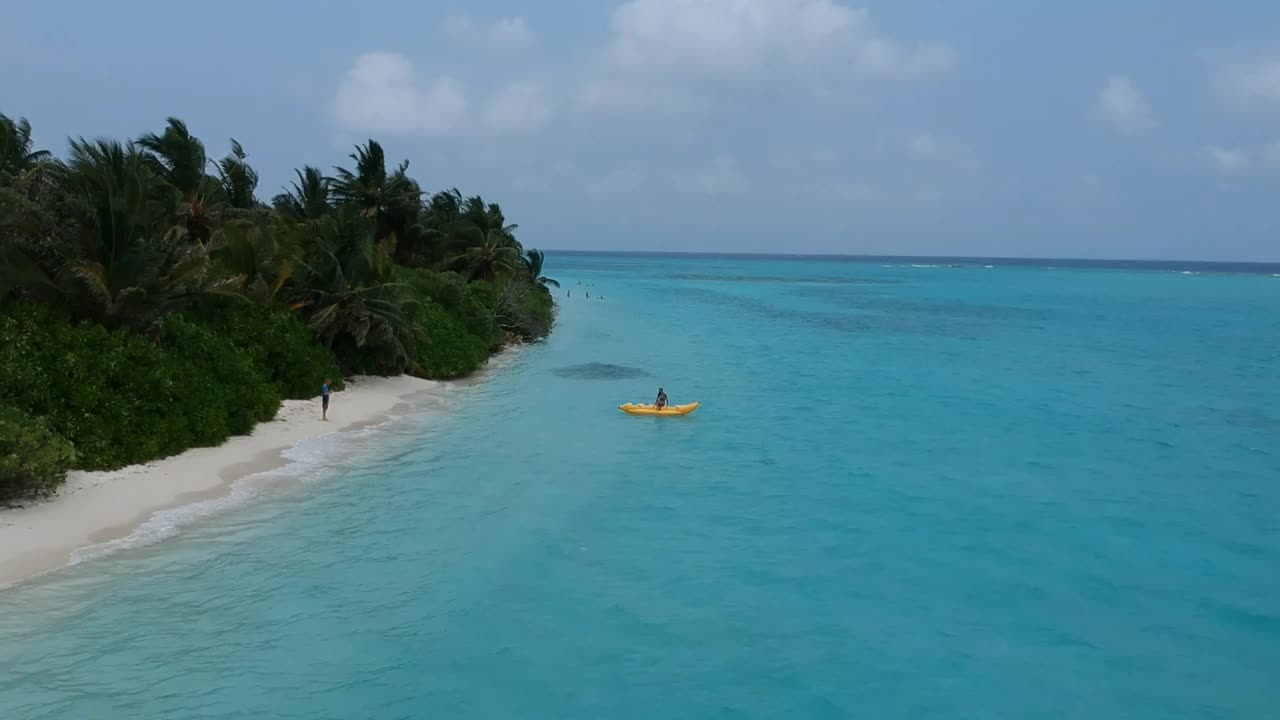 热带海滩的风景。美丽的海浪，绿色的棕榈树，蓝色的水和天空的马尔代夫视频下载