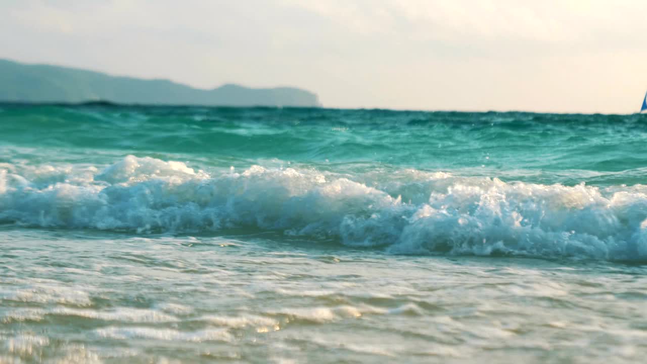 海浪拍打着沙滩。阳光反射在水面上。美丽的傍晚自然海洋背景。慢动作镜头。长滩岛,菲律宾。视频素材